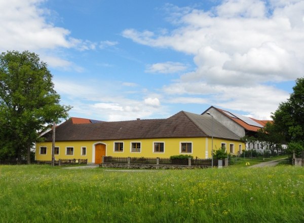 Biohof Weißensteiner, © Wolfgang Weißensteiner Gelbes Bauernhaus auf einer grünen Wiese mit blauem Himmel und Wolken.