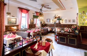 Innenansicht einer gem&uuml;tlichen Pizzeria mit roten Tischdecken und dekorativen Lampen.