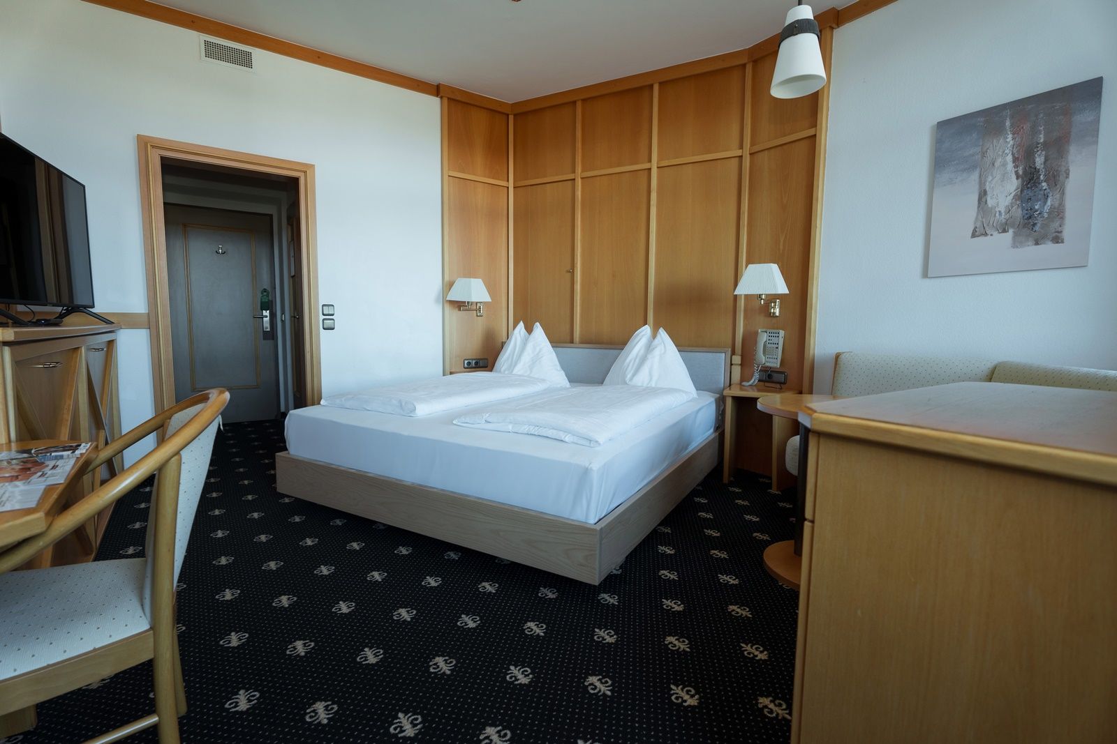 Ein Hotelzimmer mit Doppelbett, Holzmöbeln und einem Fernseher.