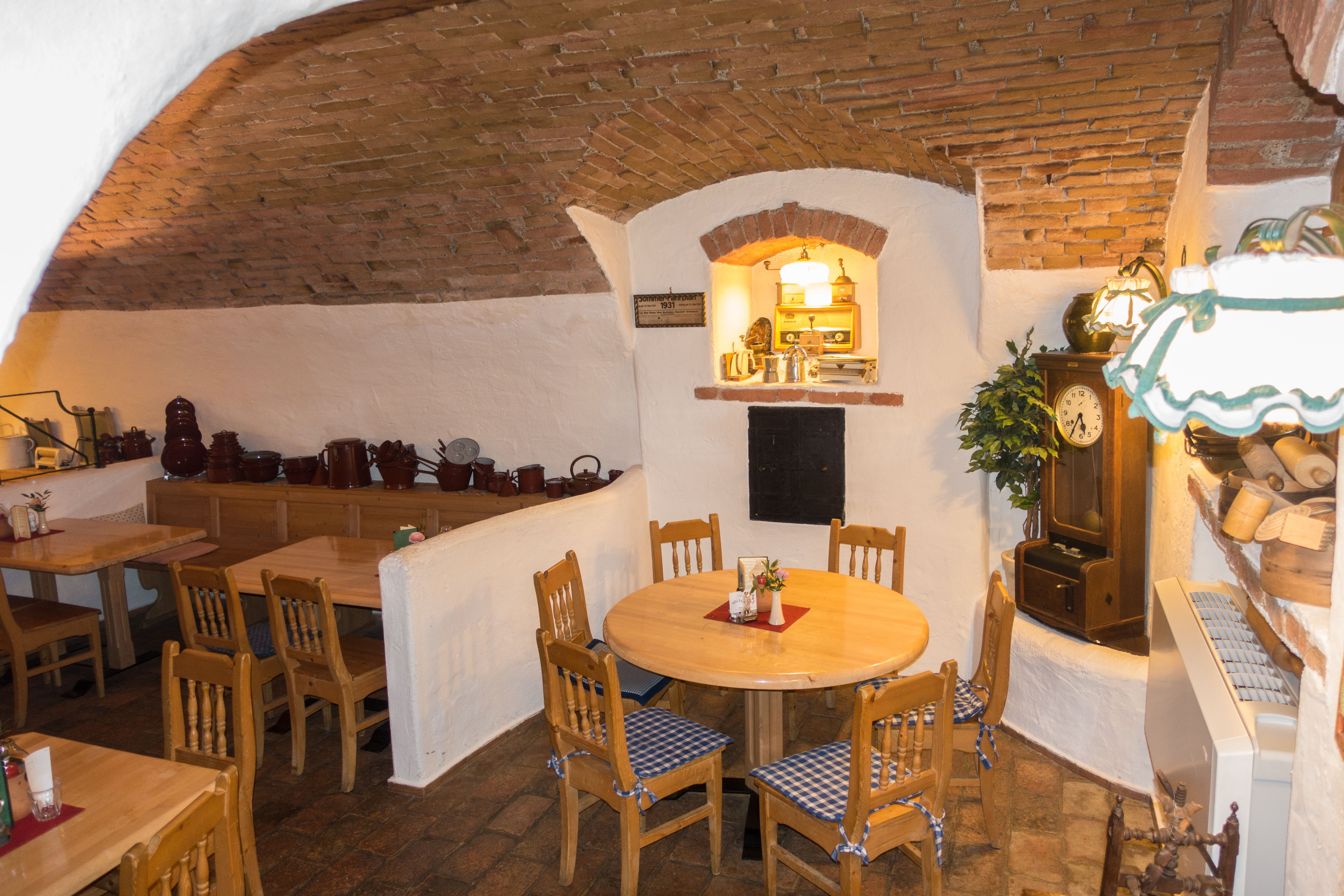 Gemütlicher Gastraum mit Holztischen und -stühlen, Ziegelgewölbe und rustikaler Dekoration.