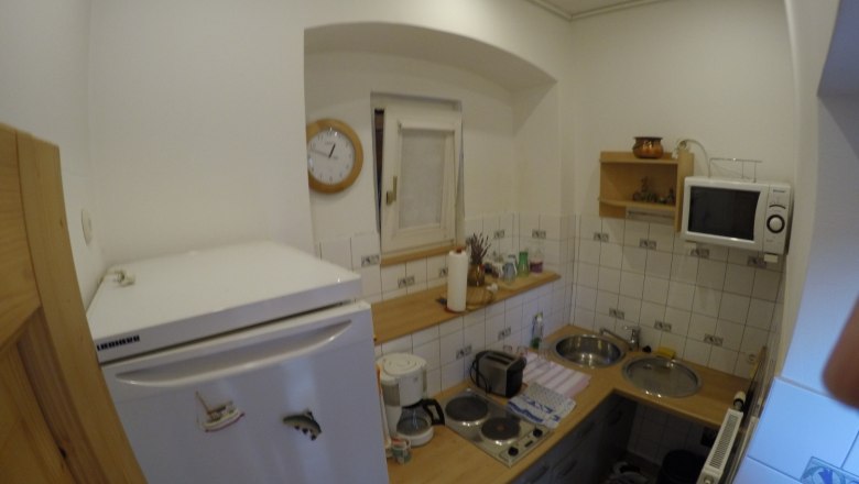 Kleine K&uuml;che mit K&uuml;hlschrank, Mikrowelle, Herd und Sp&uuml;le.