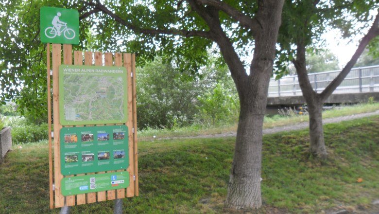 Radstartplatz-Tafel in Lanzenkirchen mit Karte und Informationen, umgeben von B&auml;umen.