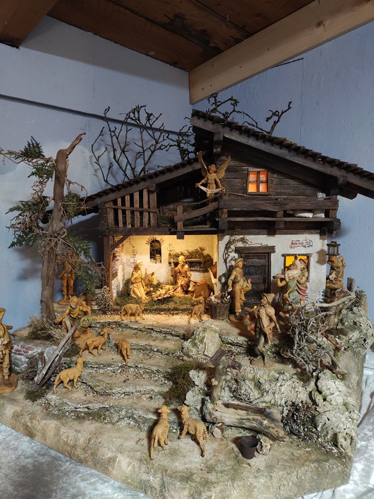 Detailreiche Weihnachtskrippe mit Figuren und Tieren in einem rustikalen Stall.