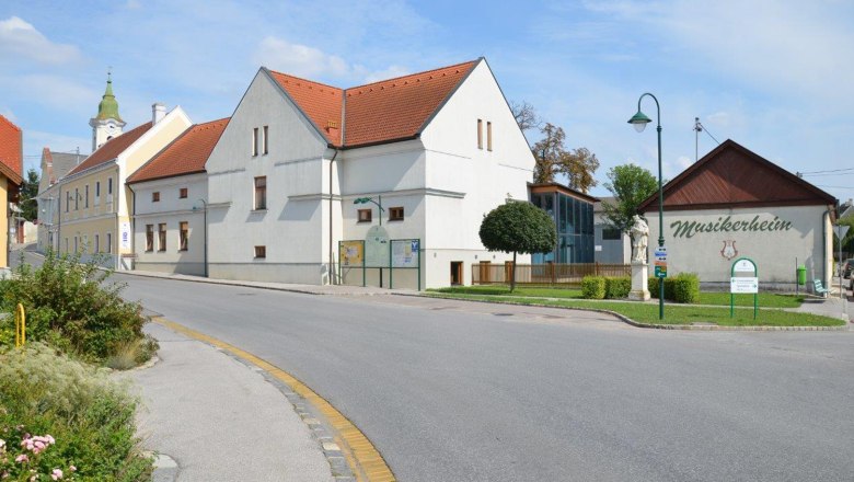 Straßenszene in Hohenruppersdorf mit Musikerheim und Kirche im Hintergrund.