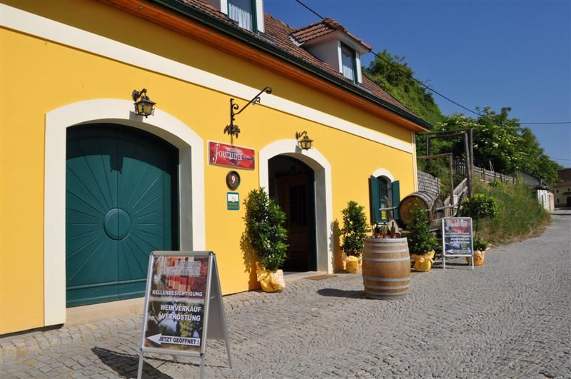 Gelbes Gebäude mit Weinkeller und Werbetafeln davor.