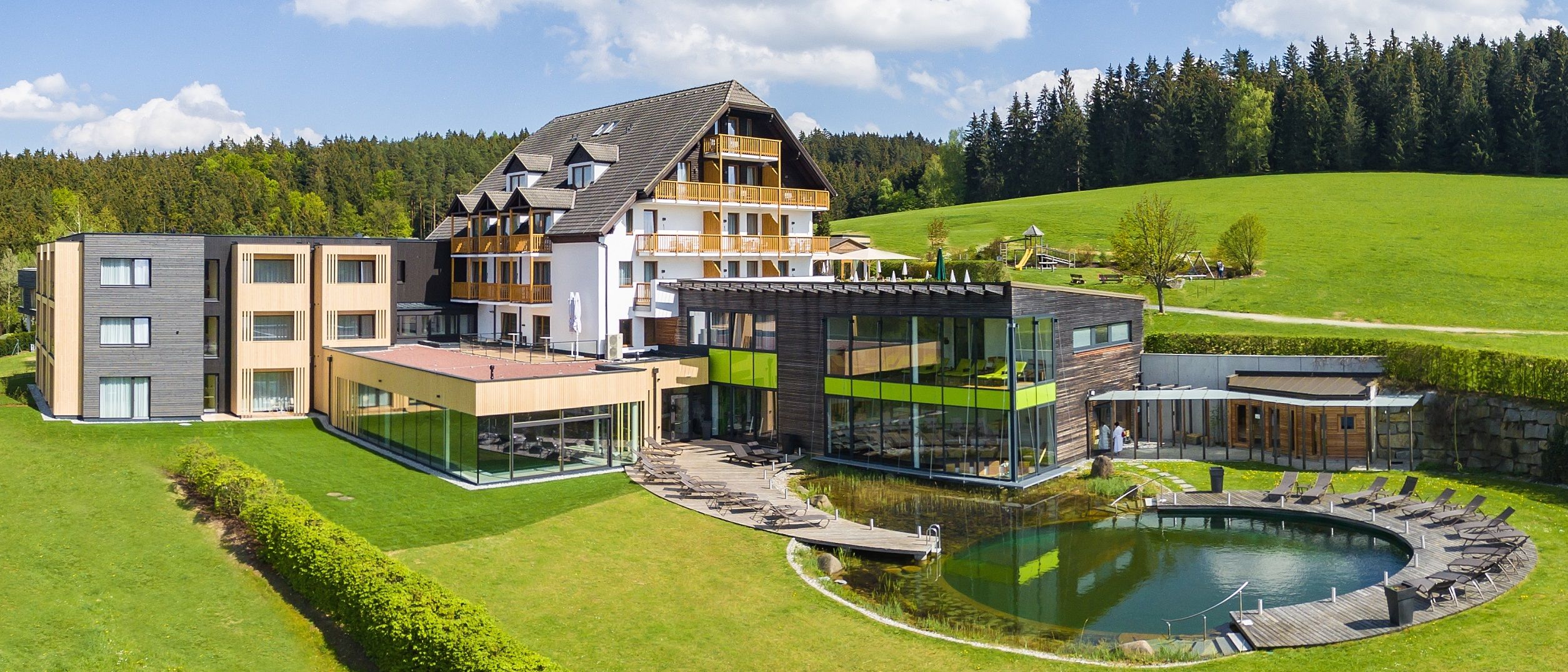 Hotel Schwarz Alm mit modernem Design, umgeben von grüner Landschaft und Wald.