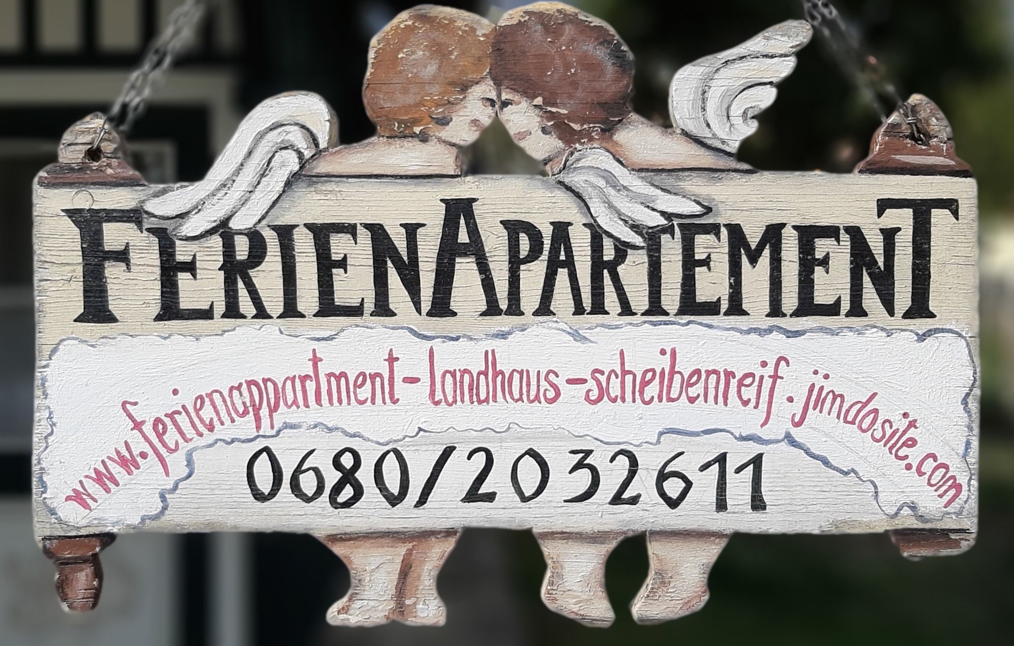 Holzschild mit der Aufschrift 'Ferienapartement' und zwei Engeln.