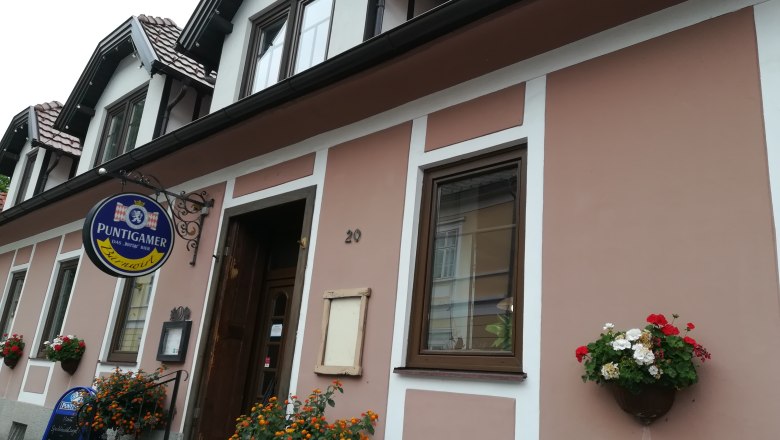 Au&szlig;enansicht eines Geb&auml;udes mit Schild 'Puntigamer' und Blumendekoration.