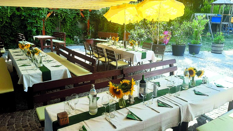 Gedeckte Tische im Freien mit Sonnenblumen und gelben Sonnenschirmen.