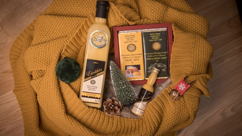 Geschenkset mit Eierlik&ouml;r, Schokolade und Dekoration auf gelbem Strickstoff.