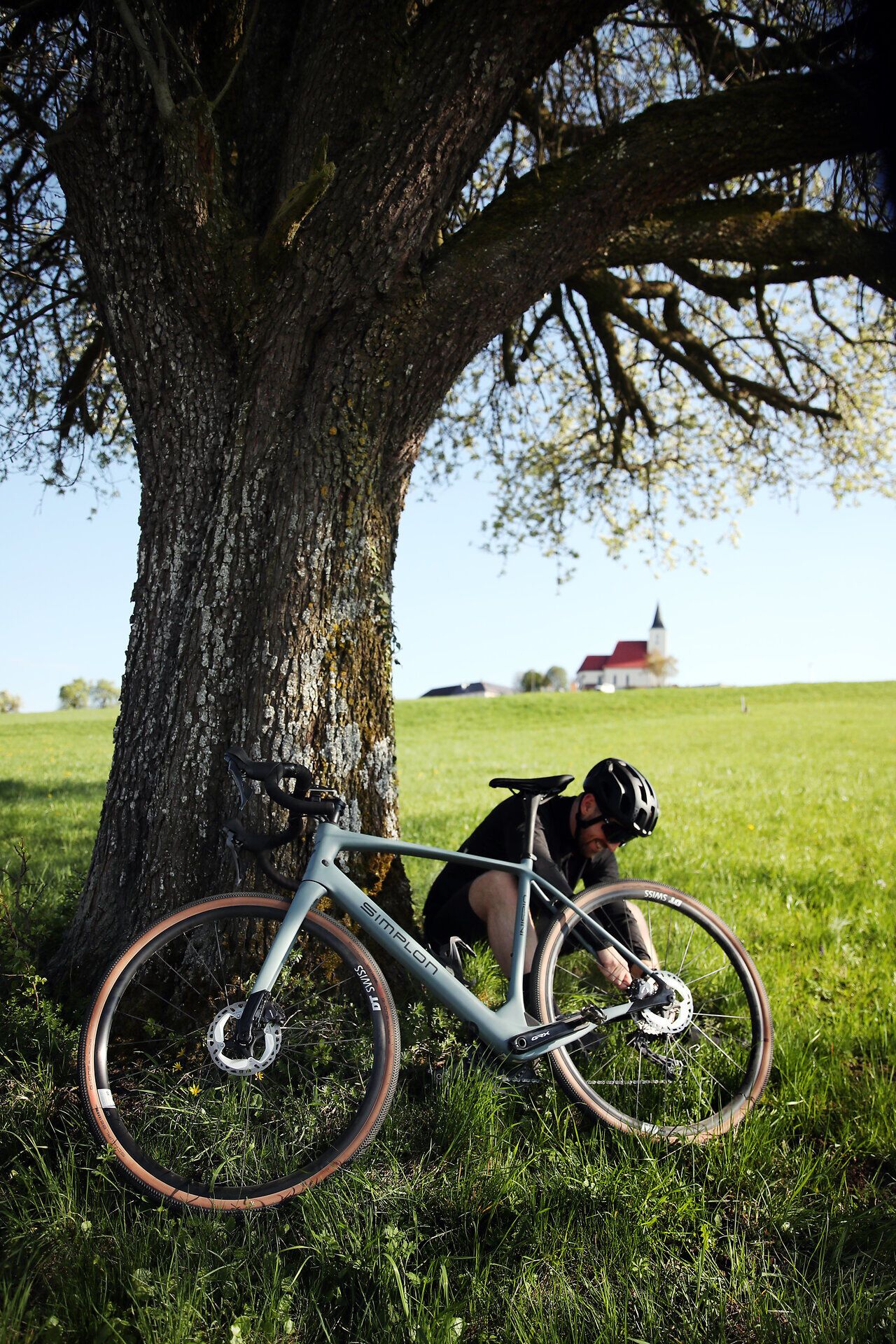 Radfahrer macht Pause unter einem schattigen Baum.