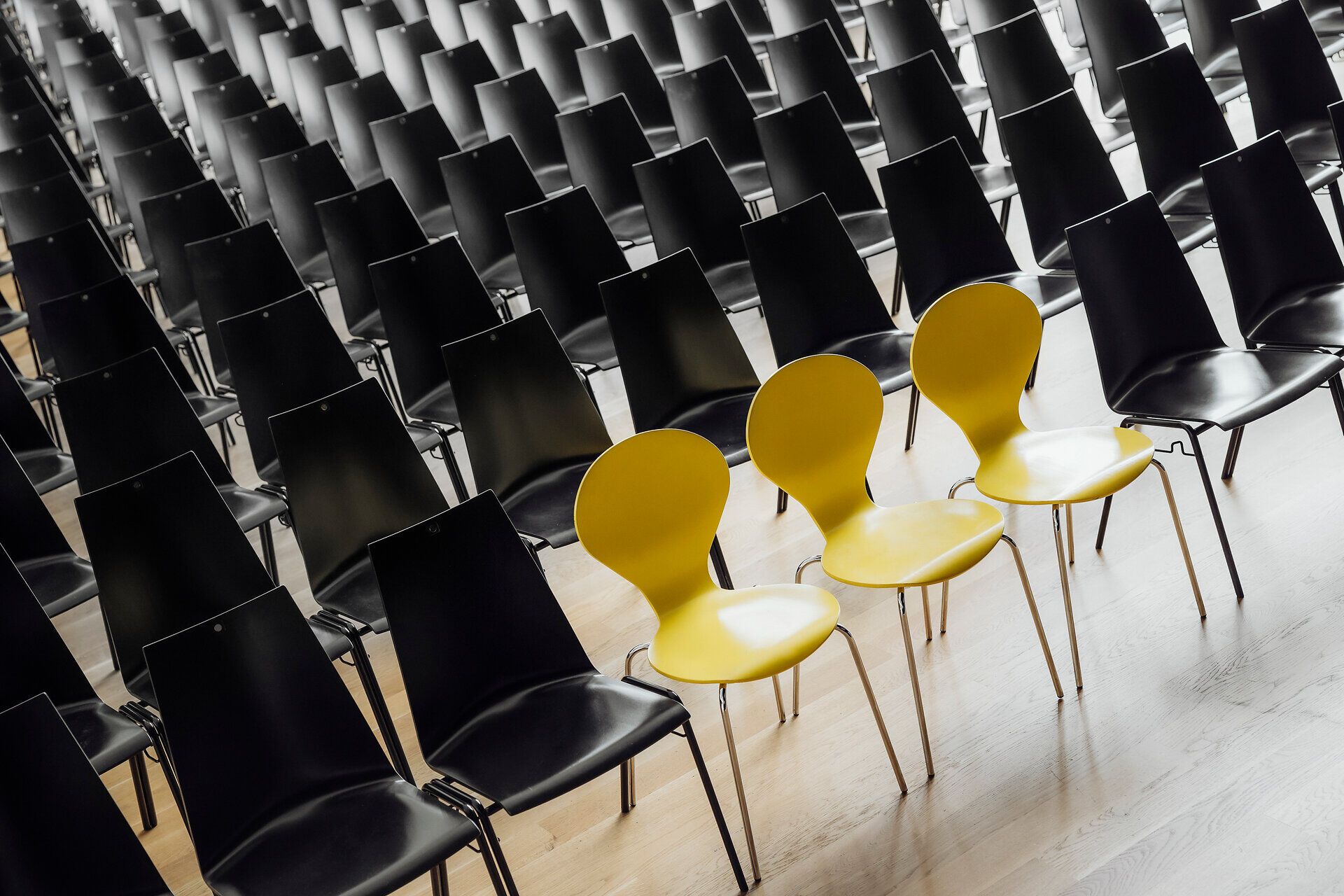 Eine beeindruckende Anordnung von Stühlen erwartet die Gäste in der Stadthalle. Die harmonische Kombination aus schwarzen und gelben Stühlen schafft eine einladende Atmosphäre für Veranstaltungen und Zusammenkünfte. Hier wird Gemeinschaft und Austausch großgeschrieben.