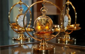 Goldene Taschenuhr in einem dekorativen Ständer, reflektiert in einem Spiegel.