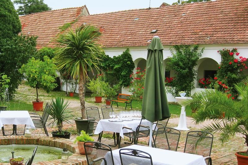 Ein idyllischer Innenhof mit Tischen, Stühlen, Pflanzen und einem Brunnen.