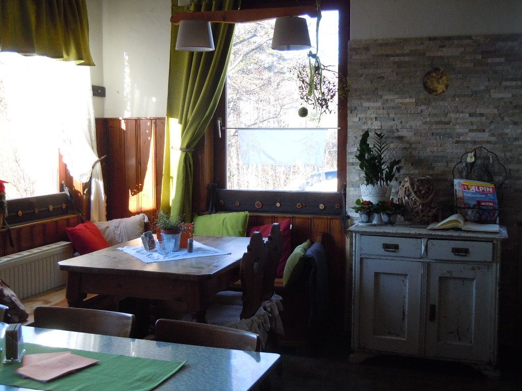 Gemütliche Ecke in einem Raum mit Holztisch, Kissen und Pflanzen.