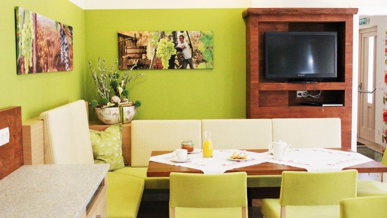 Gemütlicher Essbereich mit grünen Wänden, Holzmöbeln und einem Fernseher.