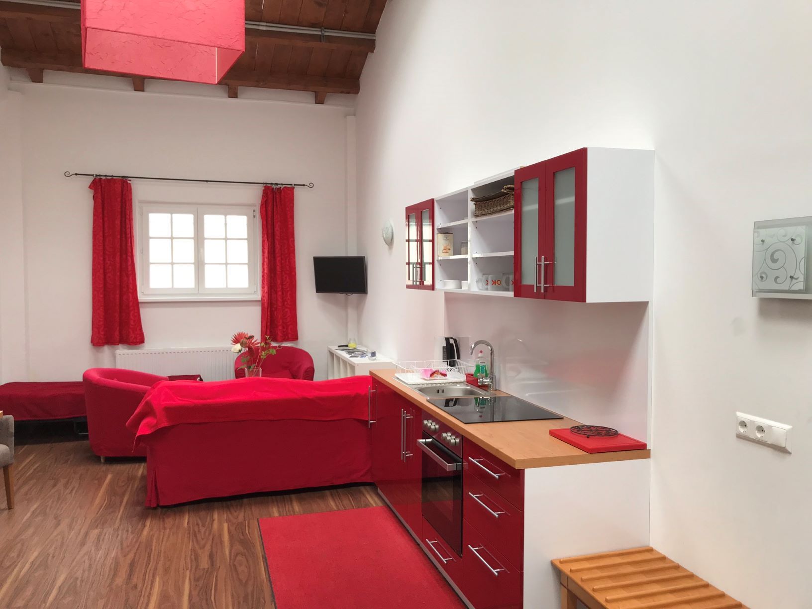Moderne Loftküche mit roten Akzenten und Holzboden.