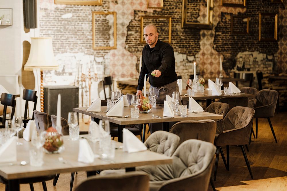 Kellner deckt stilvoll gedeckten Tisch in elegantem Restaurant ein.
