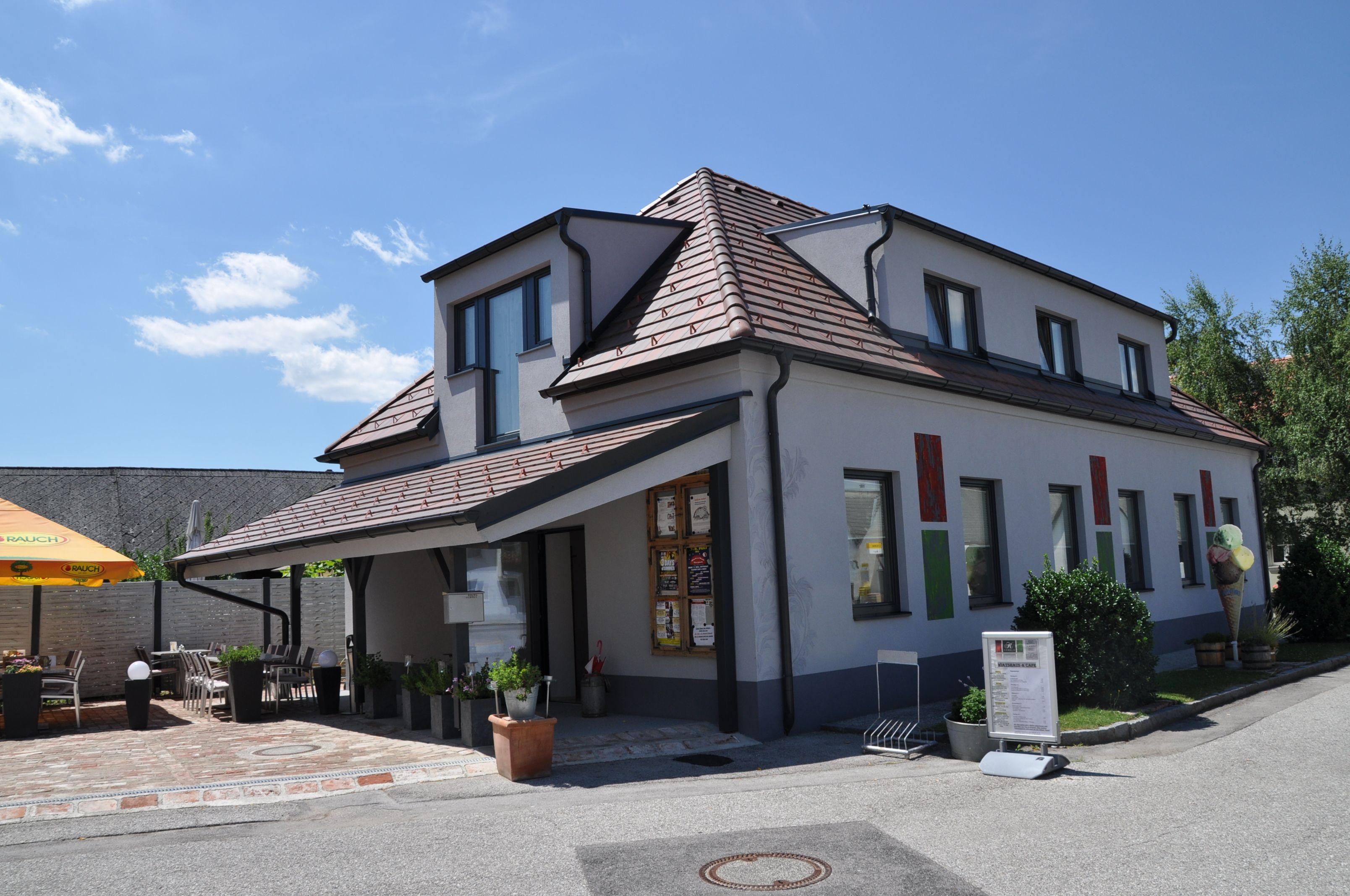 Ein modernes Gebäude mit Terrasse und Sonnenschirm an einem sonnigen Tag.