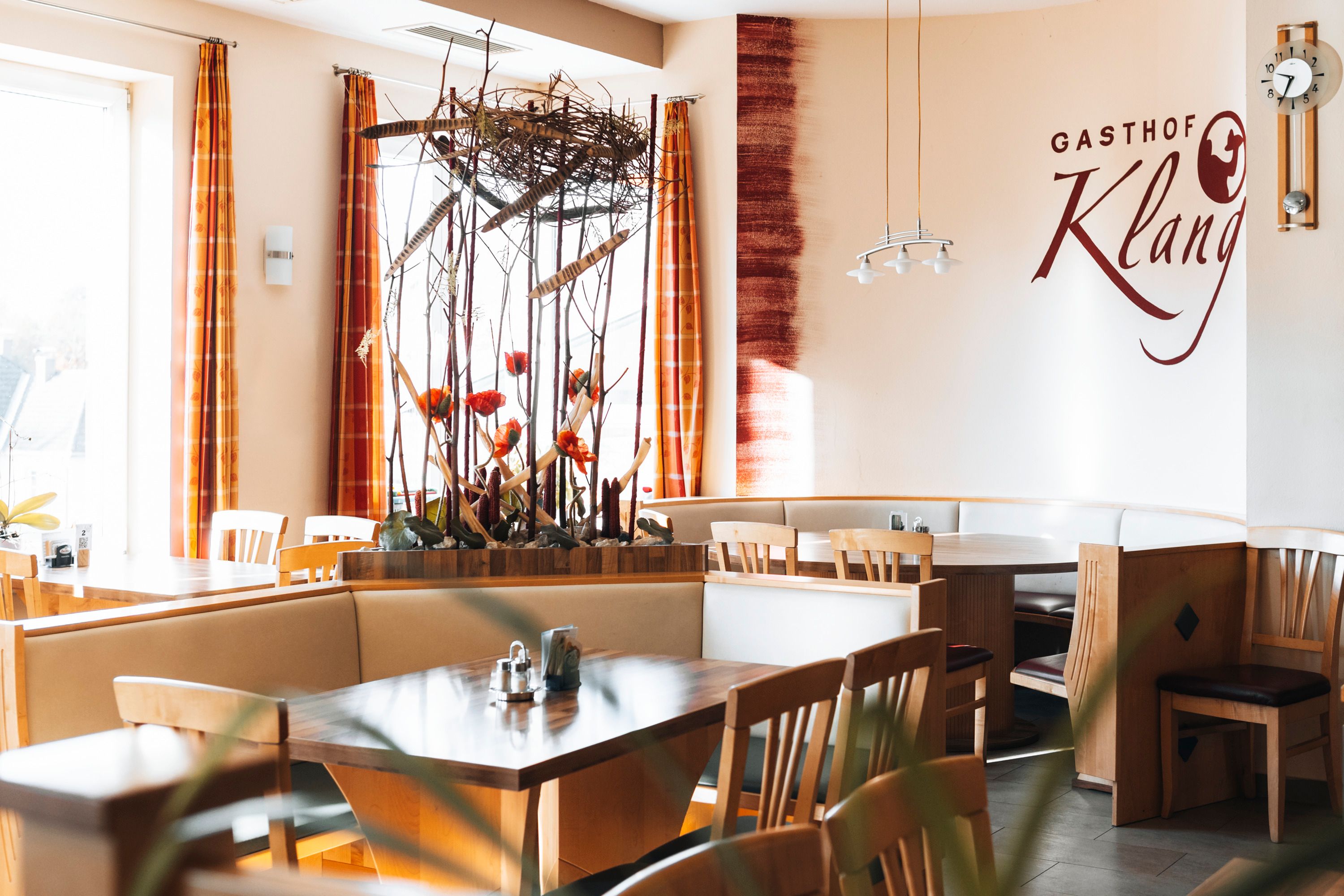 Innenansicht eines Restaurants mit Holzmöbeln und dekorativen Pflanzen.