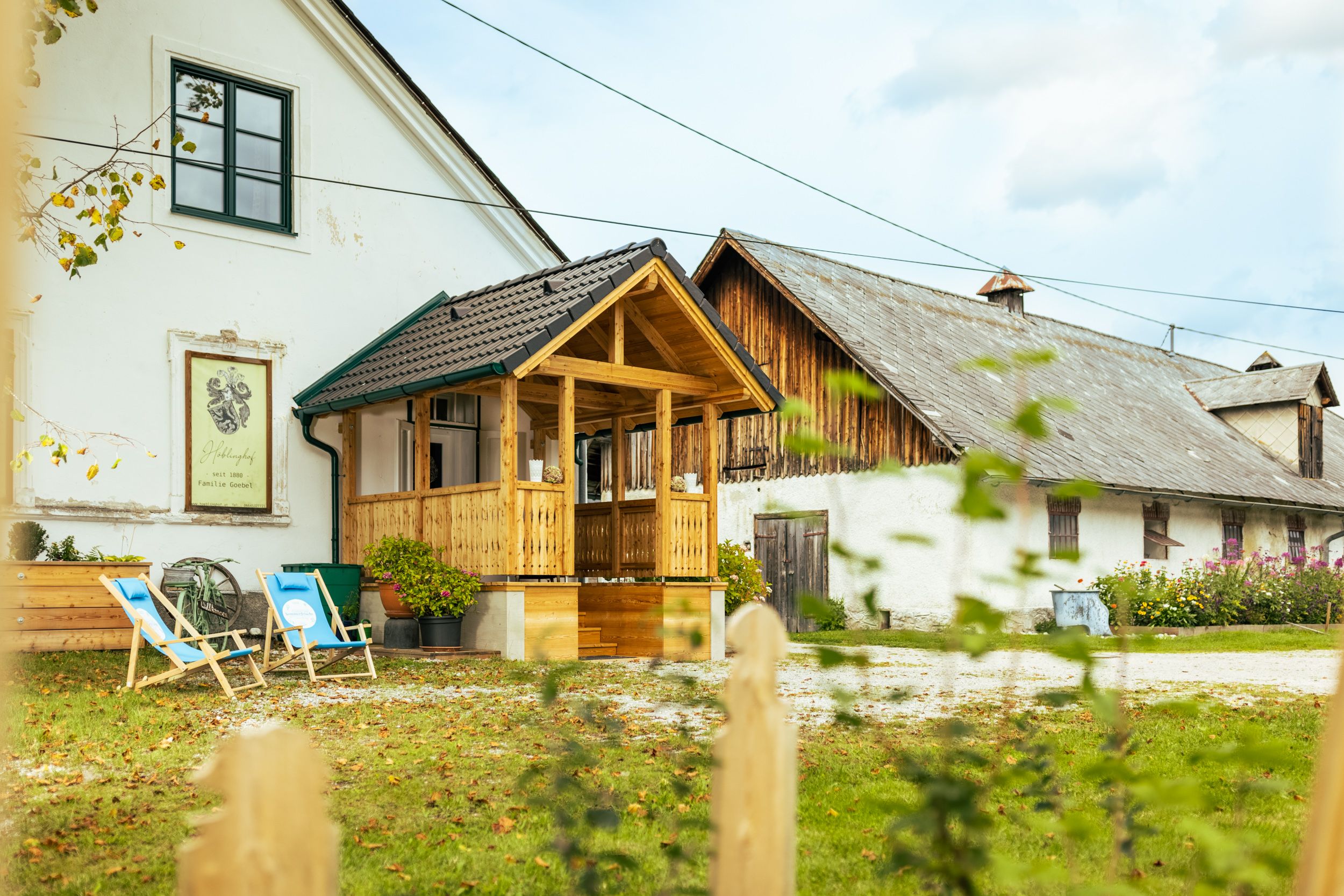 Ein traditionelles Bauernhaus mit Holzbalkon und Liegestühlen im Garten.
