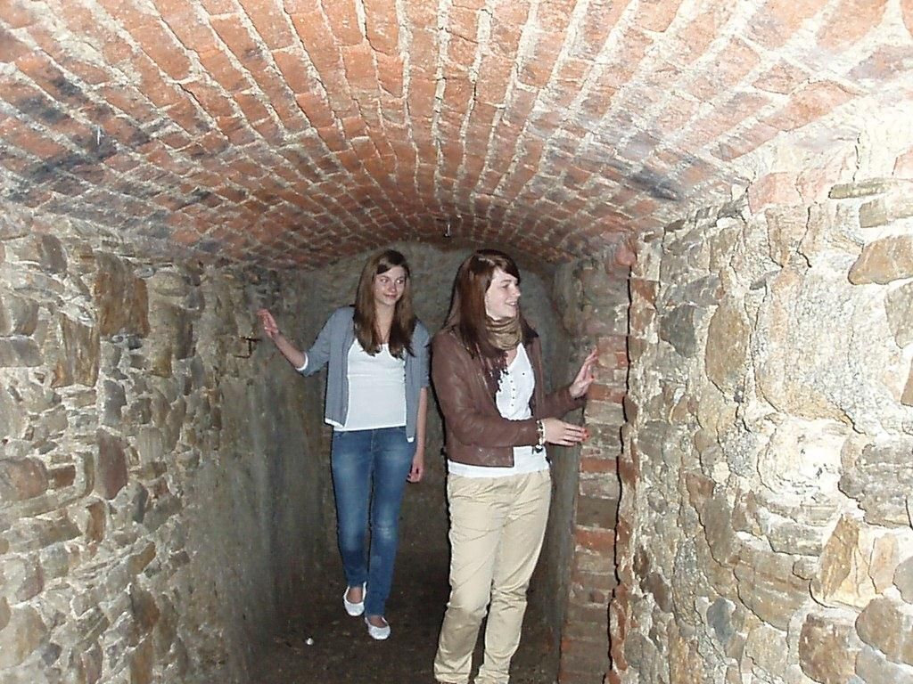 Zwei Frauen in einem schmalen, gemauerten Tunnel mit Ziegeldecke.
