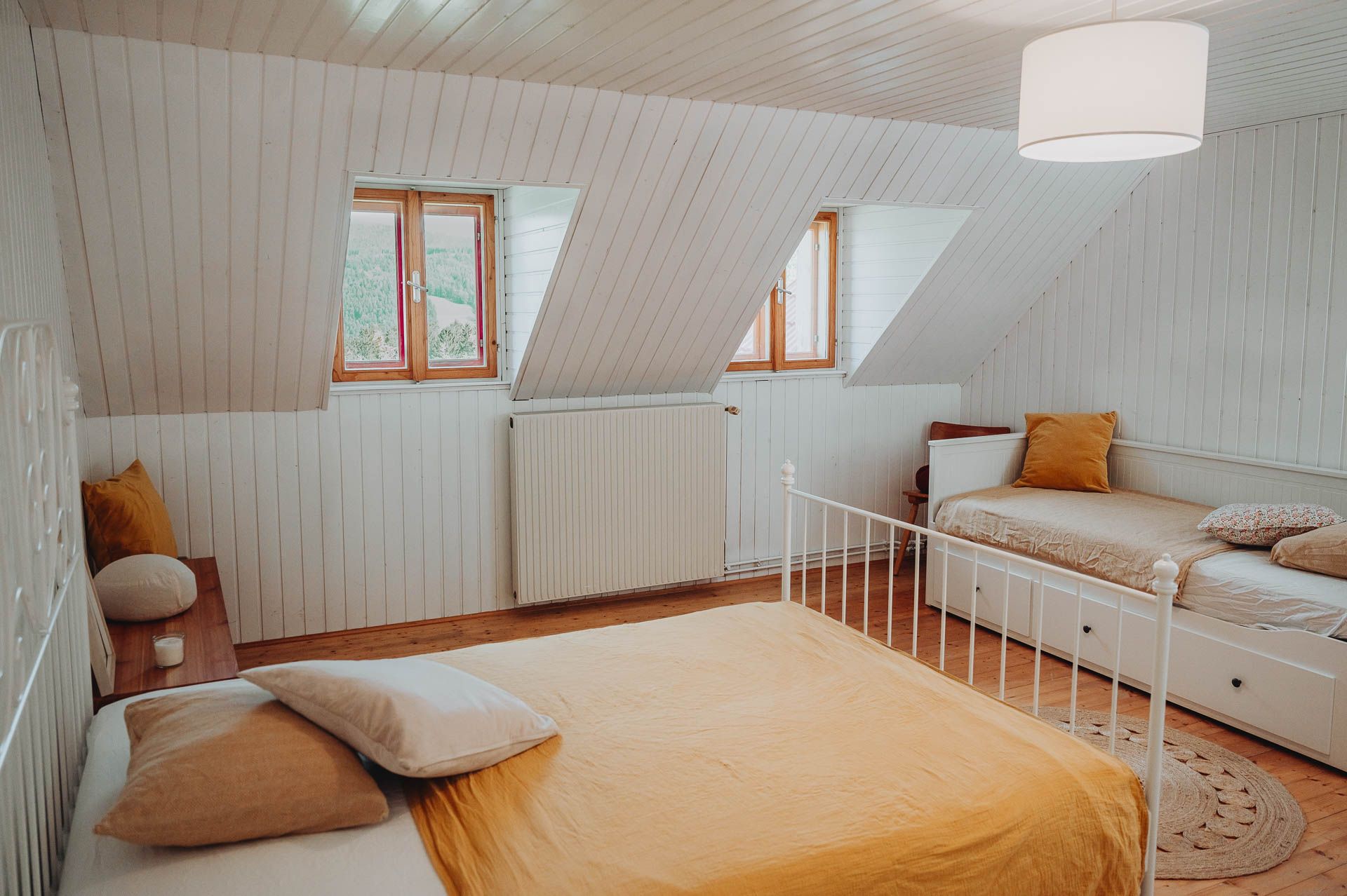 Gemütliches Schlafzimmer mit zwei Betten, Holzboden und Dachfenstern.