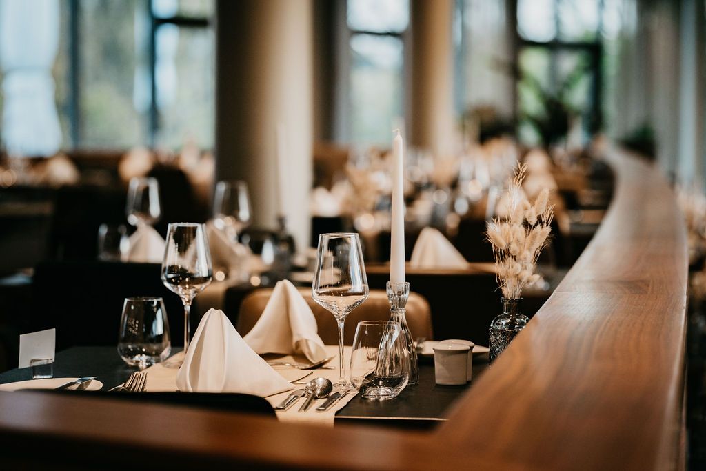 Elegantes Restaurant mit gedecktem Tisch, Weingläsern und Kerzen.