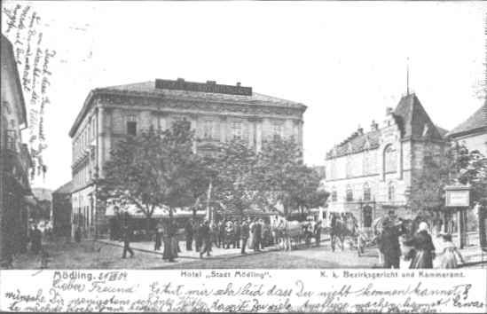 Historische Ansicht des Hotels Stadt Mödling mit Menschen und Kutschen auf der Straße.