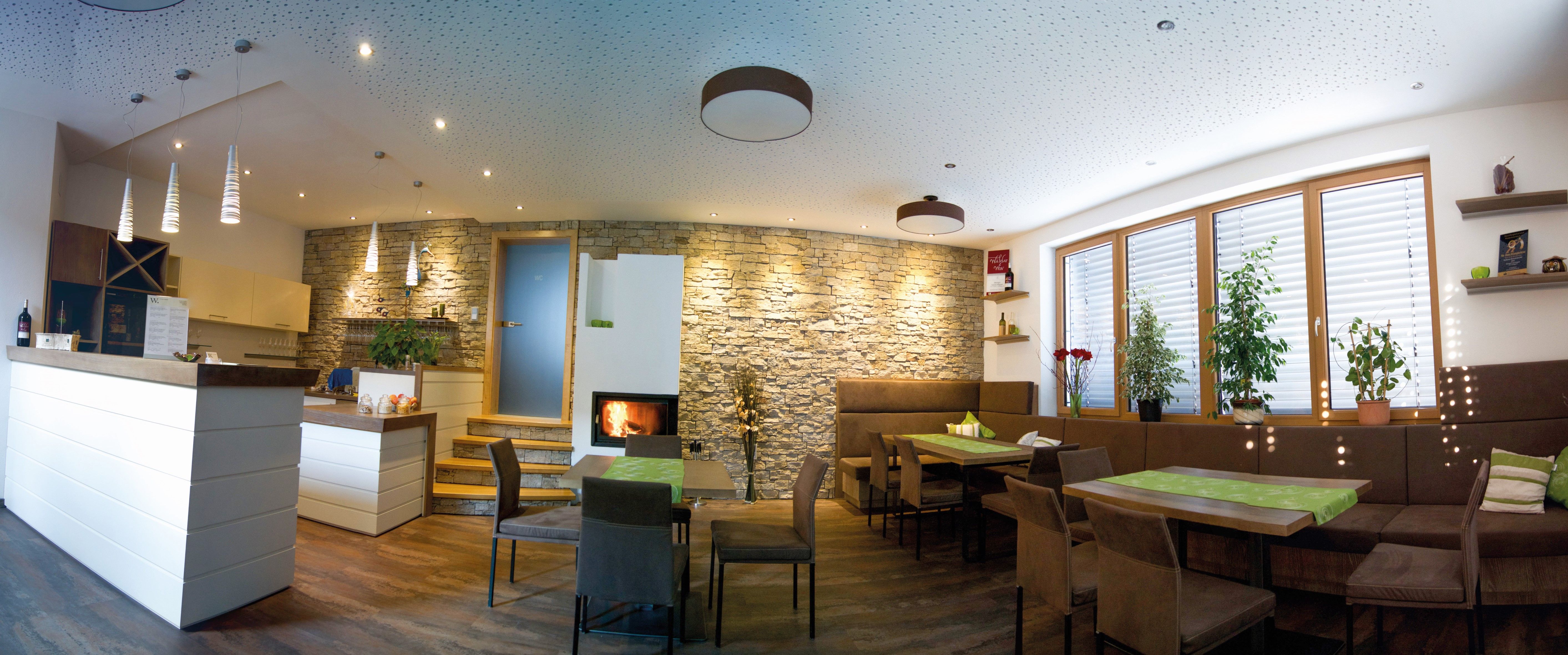 Ein moderner Verkostungsraum mit Holzmöbeln, Steinwand, Kamin und Pflanzen.