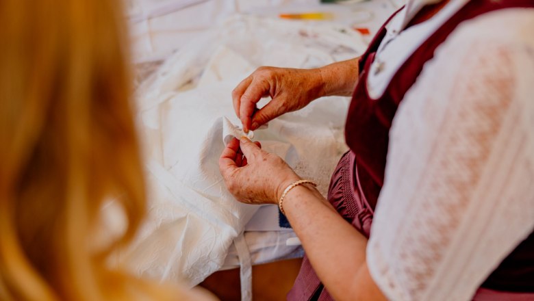 Nahaufnahme einer Person, die an einem weißen Stoff arbeitet.