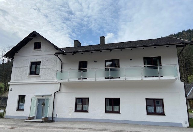 Zweist&ouml;ckiges wei&szlig;es Haus mit Balkon und blauen Himmel im Hintergrund.