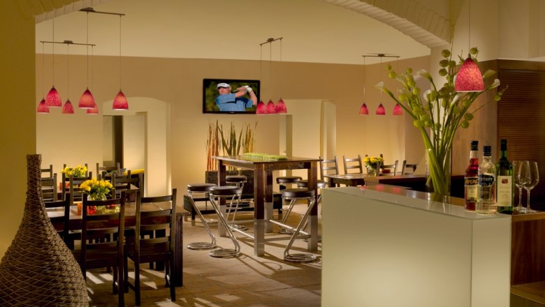 Innenansicht eines stilvollen Restaurants mit modernen Möbeln und roten Hängelampen.