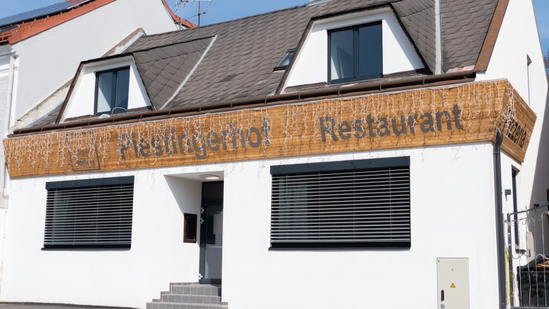 Der Piestingerhof, © Sara Grill Fassade eines Restaurants mit dem Namen Piestingerhof, dekoriert mit Lichterketten.