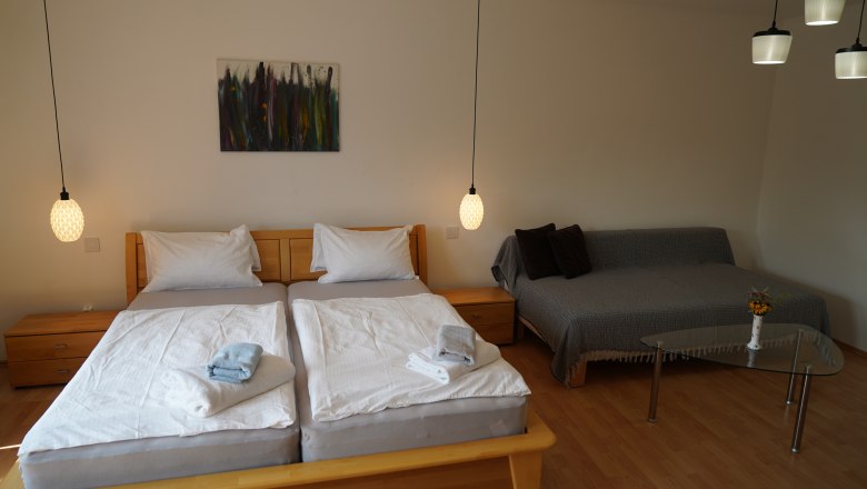 Gemütliches Schlafzimmer mit Doppelbett, Sofa und Glastisch.