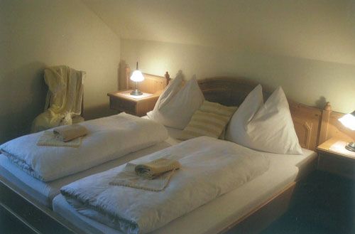 Gemütliches Gästezimmer mit Doppelbett, zwei Nachttischen und Lampen.