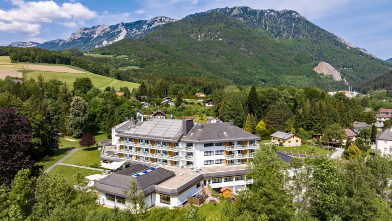 Luftaufnahme eines großen Hotels in einer grünen, bergigen Landschaft.