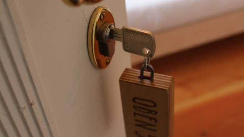 Nahaufnahme eines T&uuml;rgriffs mit Schl&uuml;ssel und Holzanh&auml;nger mit der Aufschrift 'OBEN 5'.