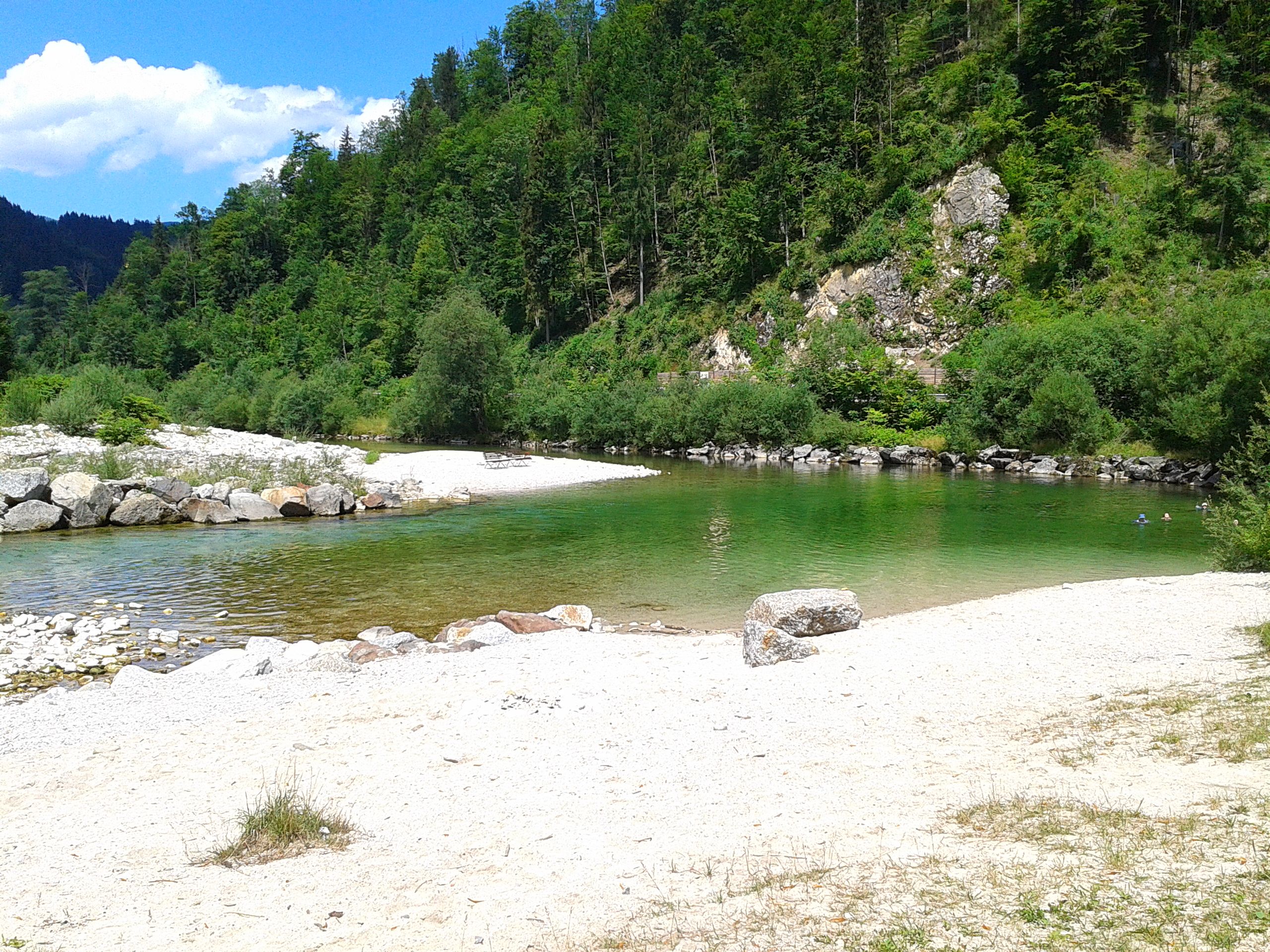 Flussbad an der Ybbs mit grünem Wasser und Kiesstrand, umgeben von bewaldeten Hügeln.
