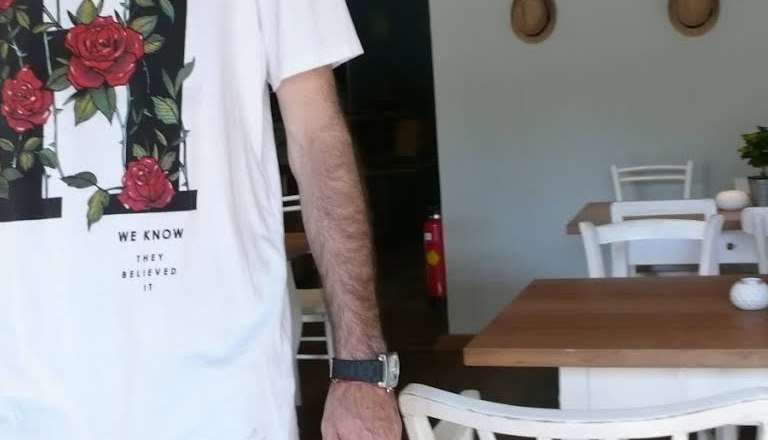 Person in wei&szlig;em T-Shirt mit Rosenmotiv in einem Caf&eacute;.