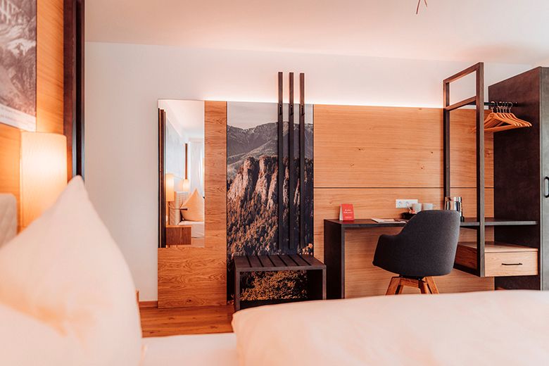 Modernes Hotelzimmer mit Holzverkleidung, Schreibtisch und Stuhl.