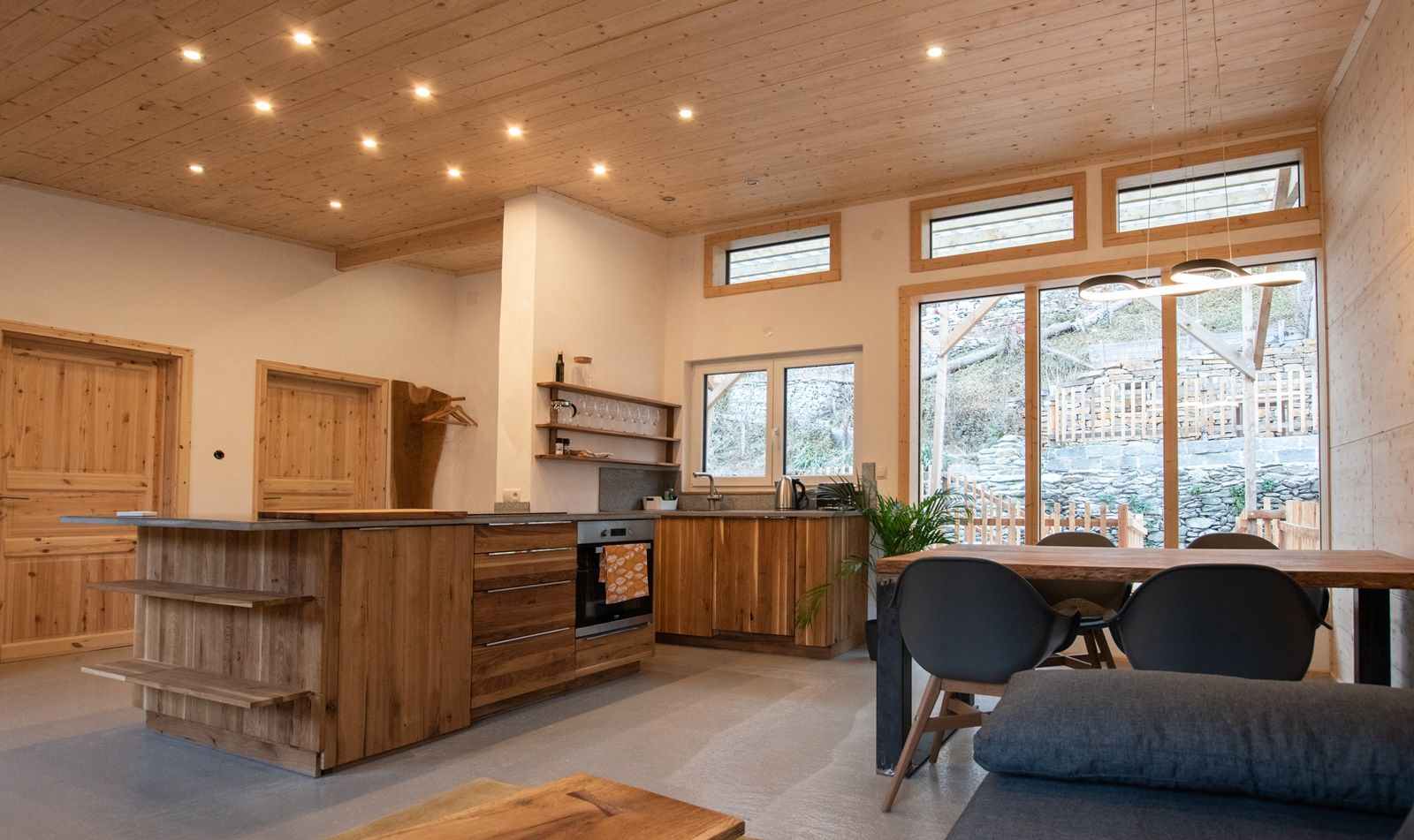 Moderne offene Küche mit Holzmöbeln und großen Fenstern.