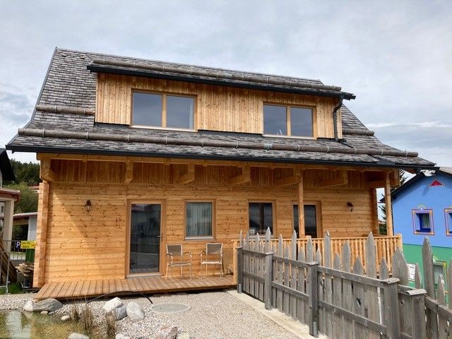 Holzchalet mit zwei Ferienwohnungen und Terrasse, umgeben von einem Holzzaun.