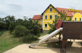 Gelbes Geb&auml;ude mit rotem Dach und Rutsche im Vordergrund.