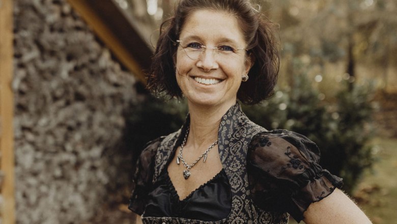 Frau in traditioneller Kleidung lächelt im Freien.