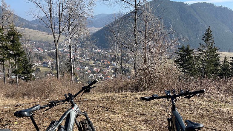 Zwei Fahrr&auml;der vor einer Berglandschaft mit Blick auf ein Tal und eine Stadt.