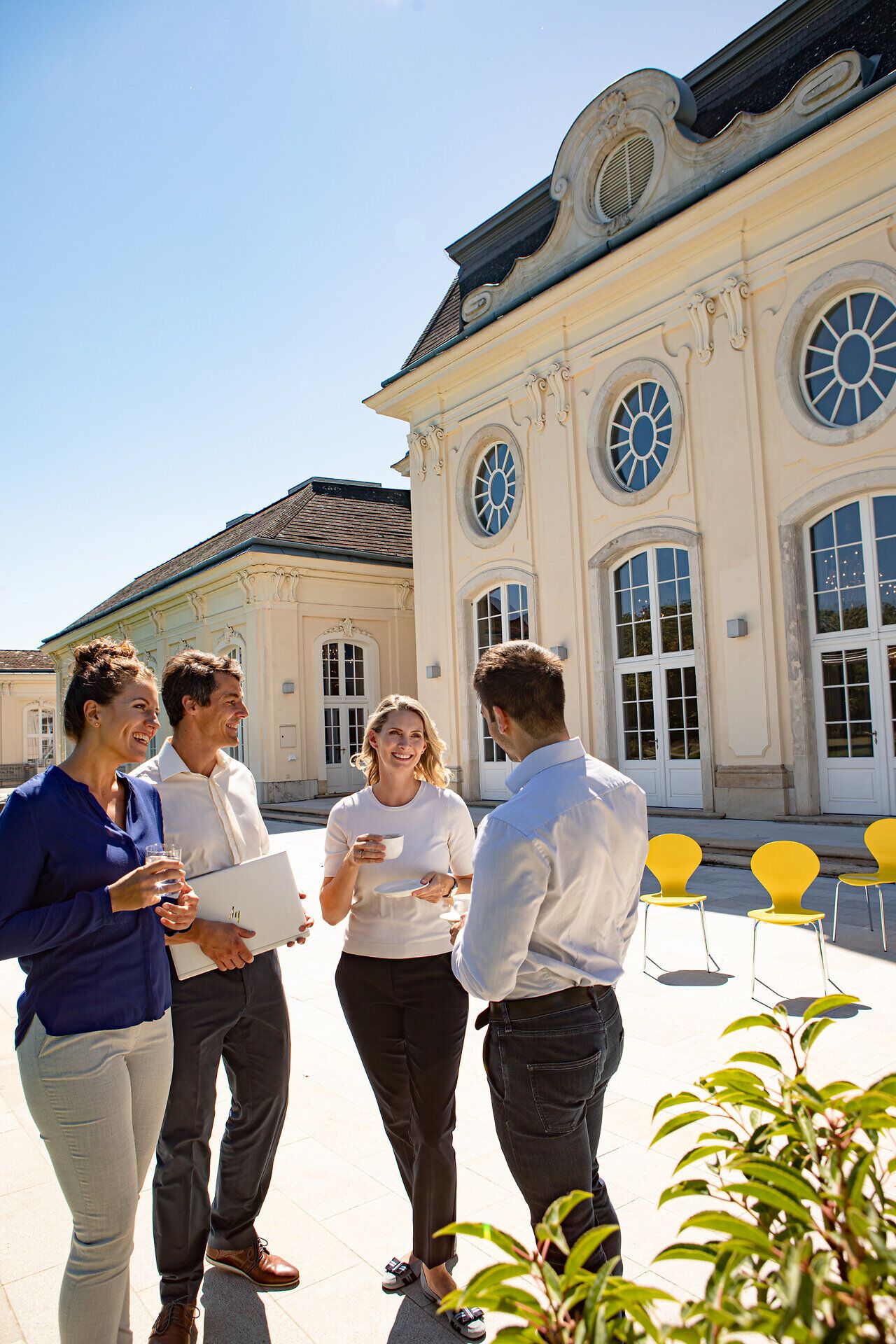 In der warmen Sonne genießen die Teilnehmer eine entspannte Pause im Freien, umgeben von der eleganten Architektur des Konferenzzentrums. Die frische Luft und die anregende Atmosphäre laden dazu ein, neue Ideen auszutauschen und die Schönheit der Natur zu erleben.