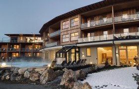 Hotelgebäude mit Außenpool und Schnee im Vordergrund.