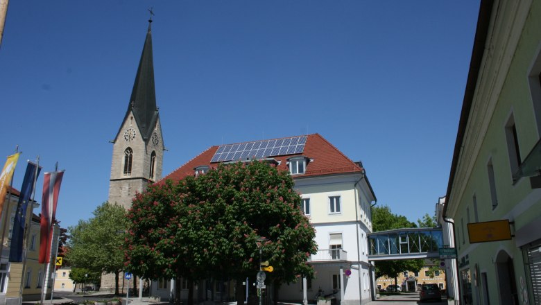 Kirchturm und Geb&auml;ude in St. Valentin mit blauem Himmel.