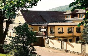 Au&szlig;enansicht der Fr&uuml;hst&uuml;ckspension Leopold Janu mit gelber Fassade und Blumenk&auml;sten.